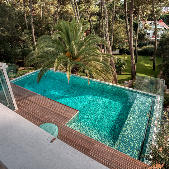 Piscine spectaculaire en mosaïque vert turquoise pour une villa dans la forêt